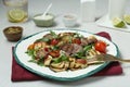 Delicious salad with beef tongue, grilled vegetables, peach, blue cheese and fork served on white table