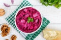 Delicious salad with boiled beets, herring, nuts, onions in a white ceramic bowl. Royalty Free Stock Photo