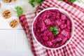 Delicious salad with boiled beets, herring, nuts, onions in a white ceramic bowl. Royalty Free Stock Photo