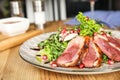 Delicious salad with roasted duck breast served on wooden table indoors, closeup Royalty Free Stock Photo