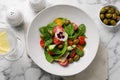 Delicious salad with vegetables and olives served on white marble table, flat lay