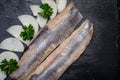 Delicious Salted Herring garnished with Yellow Onion slices and Fresh Parsley. Natural black stone. Clupea harengus.