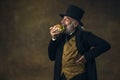 Handsome elderly gray-haired man, gentleman, aristocrat or actor eating fast food isolated on dark vintage background Royalty Free Stock Photo