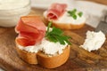 Delicious sandwiches with cream cheese and jamon on wooden board, closeup