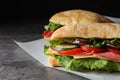 Delicious sandwiches with fresh vegetables and salami on table, closeup