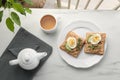 Delicious sandwiches with tuna, vegetables, boiled egg and cup of coffee on white marble table indoors, flat lay. Tasty breakfast