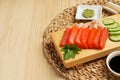 Delicious sashimi set of salmon and shrimps served with cucumbers, parsley, wasabi and soy sauce on wooden table. Space for text