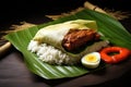 A delicious and satisfying meal consisting of rice, meat, and an egg served on a plate., Nasi Lemak wrapped in a banana leaf,