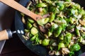 Delicious sauteed brussels sprouts with mushrooms in large skillet, wood turner, kitchen towel