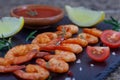 Delicious sauteed shrimps with sauce and lemon on black plate