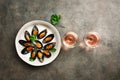 Delicious seafood mussels with spices, parsley and two glasses of pink sparkling wine in a row, dark rustic background. Top view, Royalty Free Stock Photo