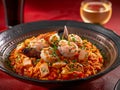Delicious Seafood Paella with Shrimp, Mussels, and Squid in Traditional Pan on Red Background Royalty Free Stock Photo