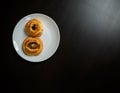 Delicious sesame buns or pies on white plate standing on black wooden table Royalty Free Stock Photo