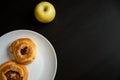 Delicious sesame buns or pies on white plate and yellow apple on black wooden table background Royalty Free Stock Photo