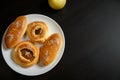 Delicious sesame buns or pies on white plate and yellow apple on black wooden table background Royalty Free Stock Photo