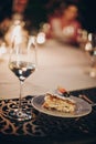 Delicious simple wedding cake slice with fruits on white plate and champagne glass on table at wedding reception outdoors in the Royalty Free Stock Photo