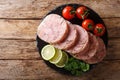 Delicious sliced Head cheese or brawn served with tomatoes, lime and cilantro closeup on a slate board. horizontal top view