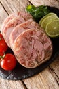 Delicious sliced Head cheese or brawn served with tomatoes, lime and cilantro closeup on a slate board. vertical Royalty Free Stock Photo