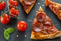 Delicious fresh cooked slices of pepperoni pizza on slate with cherry tomatoes red pepper and basil leafs Royalty Free Stock Photo