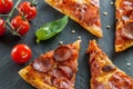 Delicious fresh cooked slices of pepperoni pizza on slate with cherry tomatoes red pepper and basil leafs Royalty Free Stock Photo