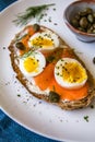 Delicious smoked salmon sourdough toast with goat cream cheese and cut boiled egg, garnished with dill, chives & pickled Capers Royalty Free Stock Photo