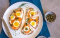 Delicious smoked salmon sourdough toast with goat cream cheese and cut boiled egg, garnished with dill, chives & pickled Capers Royalty Free Stock Photo