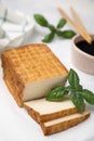 Delicious smoked tofu and basil on tiled table, closeup Royalty Free Stock Photo