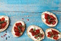 Delicious snack and appetizer. Bread slices with cream cheese and sun dried tomatoes on wooden table from above.