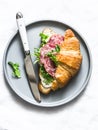 Delicious snack - salami sausage, cream cheese, green salad  croissant sandwich on a light background, top view Royalty Free Stock Photo