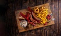 Delicious snacks with grilled sausages, fried potato, onion rings and two glasses of beer on wooden board in rustic Royalty Free Stock Photo