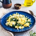 Delicious soft scrambled eggs with spinach and feta on a rustic mediterranean table in morning light Royalty Free Stock Photo