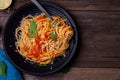 Delicious spaghetti pasta with prawns and cheese served on a black plate on a wooden table Italian recipe tomato sauce vegetables Royalty Free Stock Photo