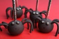 Delicious spider shaped cake pops on red background, closeup. Halloween treat