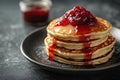 Delicious stack of fluffy pancakes topped with vibrant fruit jam served on a sleek dark plate Royalty Free Stock Photo
