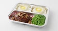 Delicious steak meal in red and white checkered plastic container with mashed potatoes, fried egg, and green peas Royalty Free Stock Photo