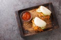 Delicious steamed bao buns sandwiches with pulled pork close-up on a wooden tray. horizontal top view
