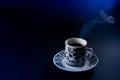 Delicious steaming hot coffee in white porcelain cup on black background