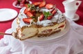 Delicious strawberries cream cake decorated with fresh cut strawberries on a white plate on the red background. Royalty Free Stock Photo