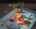 Delicious strawberry and cottage cheese sandwiches sandwiches on a wooden board tray, in the background a bouquet with forget-me- Royalty Free Stock Photo