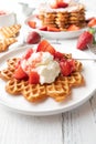 Strawberry dessert with fresh baked waffles, whipped cream and strawberry sauce on a plate on white table background Royalty Free Stock Photo