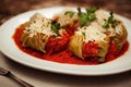 Delicious stuffed cabbage rolls on plate drizzled with tomato sauce and sprinkled with greens