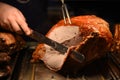 Golden whole roast turkey joint of meat being carved with a knife and the hand is visible