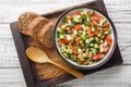 Delicious summer salad of cucumber tomato bell pepper onion seasoned with olive oil close-up in a bowl on a board. horizontal top