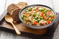 Delicious summer salad of cucumber tomato bell pepper onion seasoned with olive oil close-up in a bowl on a board. horizontal