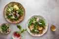 Delicious summer salad with edible flowers, vegetables, fruit, micro greens and cheese on a vintage grey background. Flat lay, top