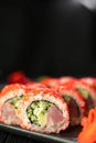 Delicious sushi roll california with tuna cucumber cheese and masago caviar on top on a stone plate on black background Royalty Free Stock Photo