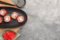 Delicious sushi rolls, soy sauce, ginger and chopsticks on grey textured table, flat lay. Space for text Royalty Free Stock Photo