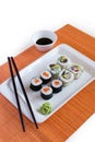 Delicious sushi rolls on white plate with chopsticks