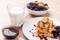 sweet Belgian waffles in the form of hearts with chocolate and berries with a glass of milk. breakfast. on a natural wooden backg Royalty Free Stock Photo