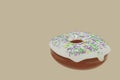 Delicious sweet chocolate donut with white sugar glaze and colorful pastry sprinkles isolated on beige background. Sweet doughnut. Royalty Free Stock Photo